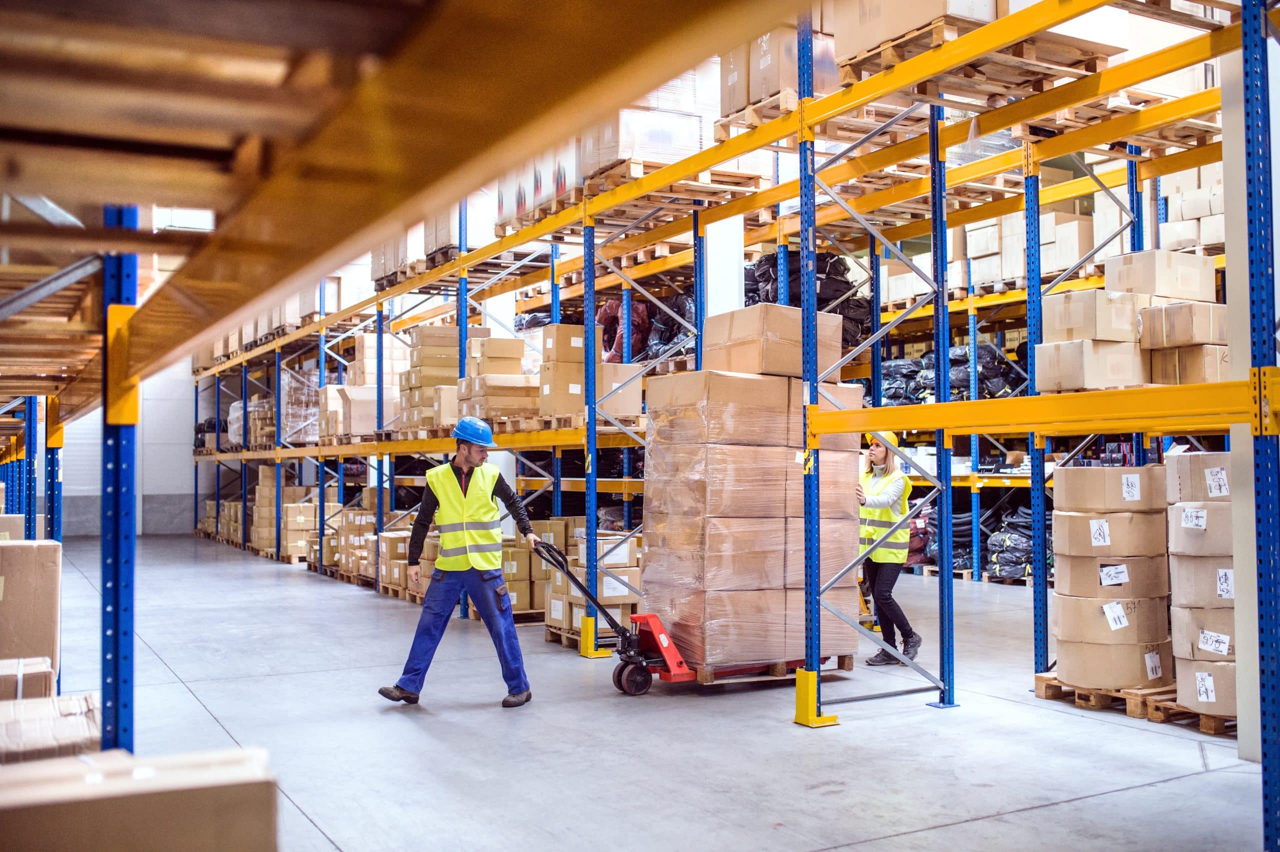 Two workers pulling a pallet of boxes in a warehouse