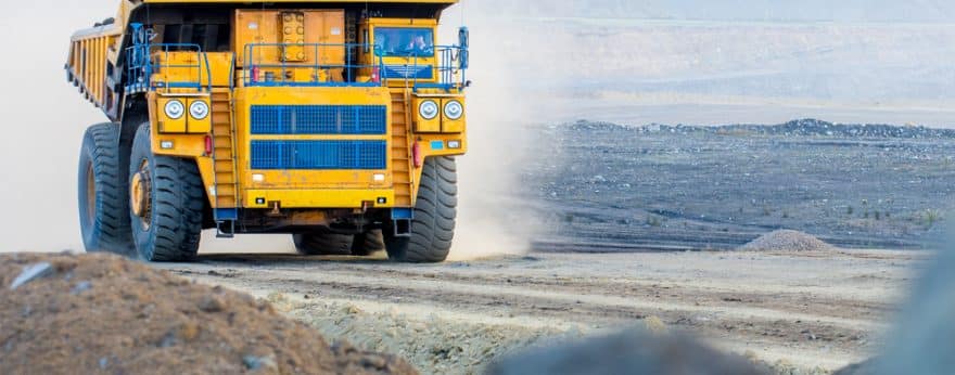 A yellow truck driving down a road on a construction site