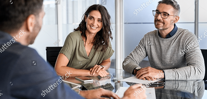 Three people having a meeting at a glass table in a modern office.
