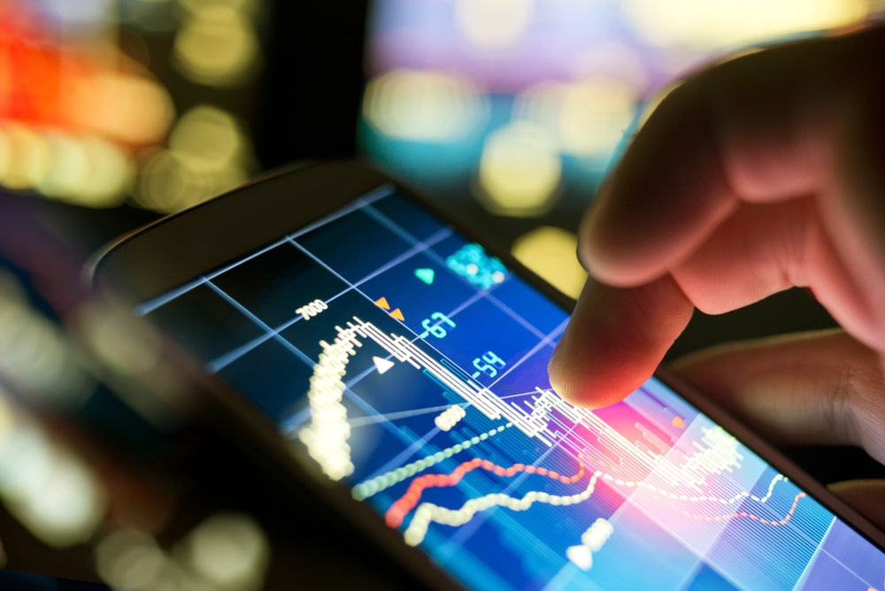 A hand interacts with a financial graph on a smartphone screen.
