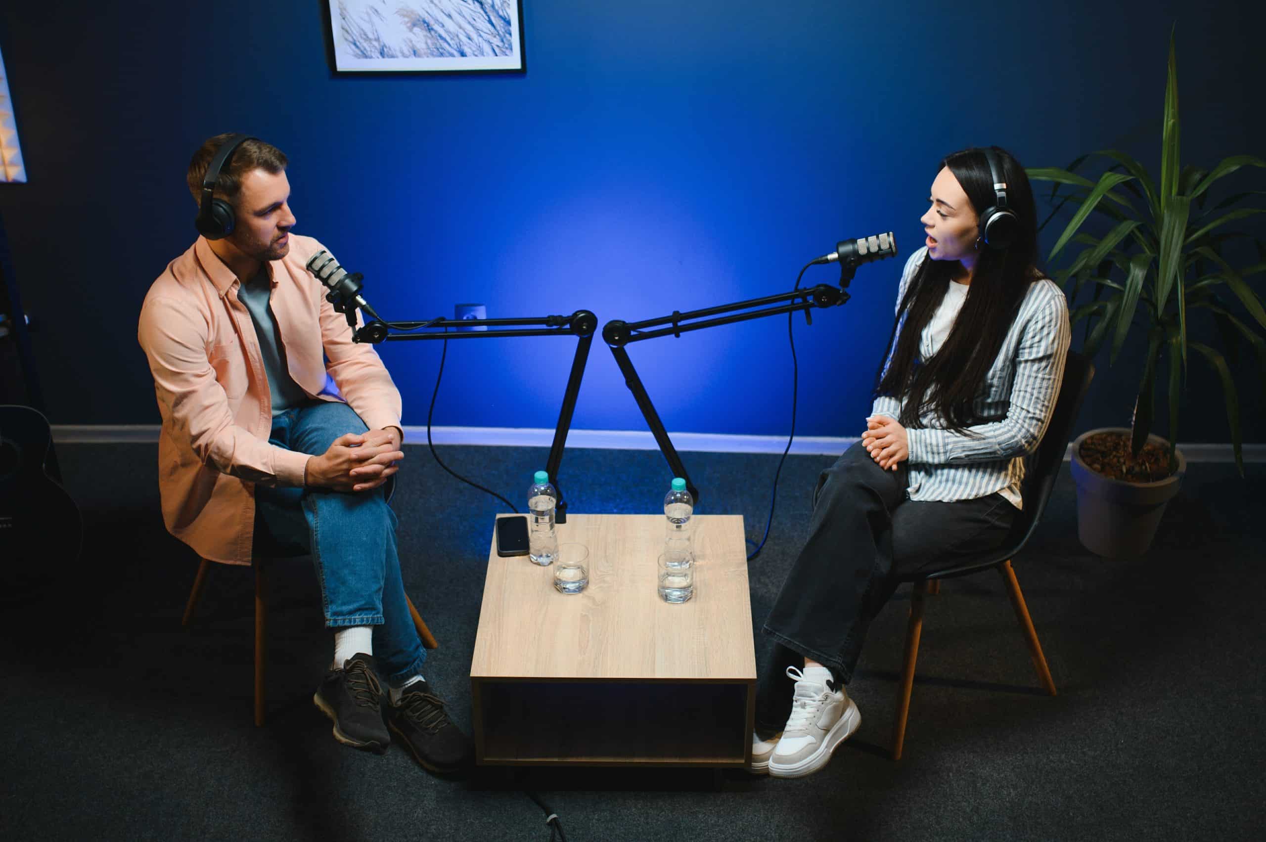 Two people recording a podcast in a studio with microphones and headphones.