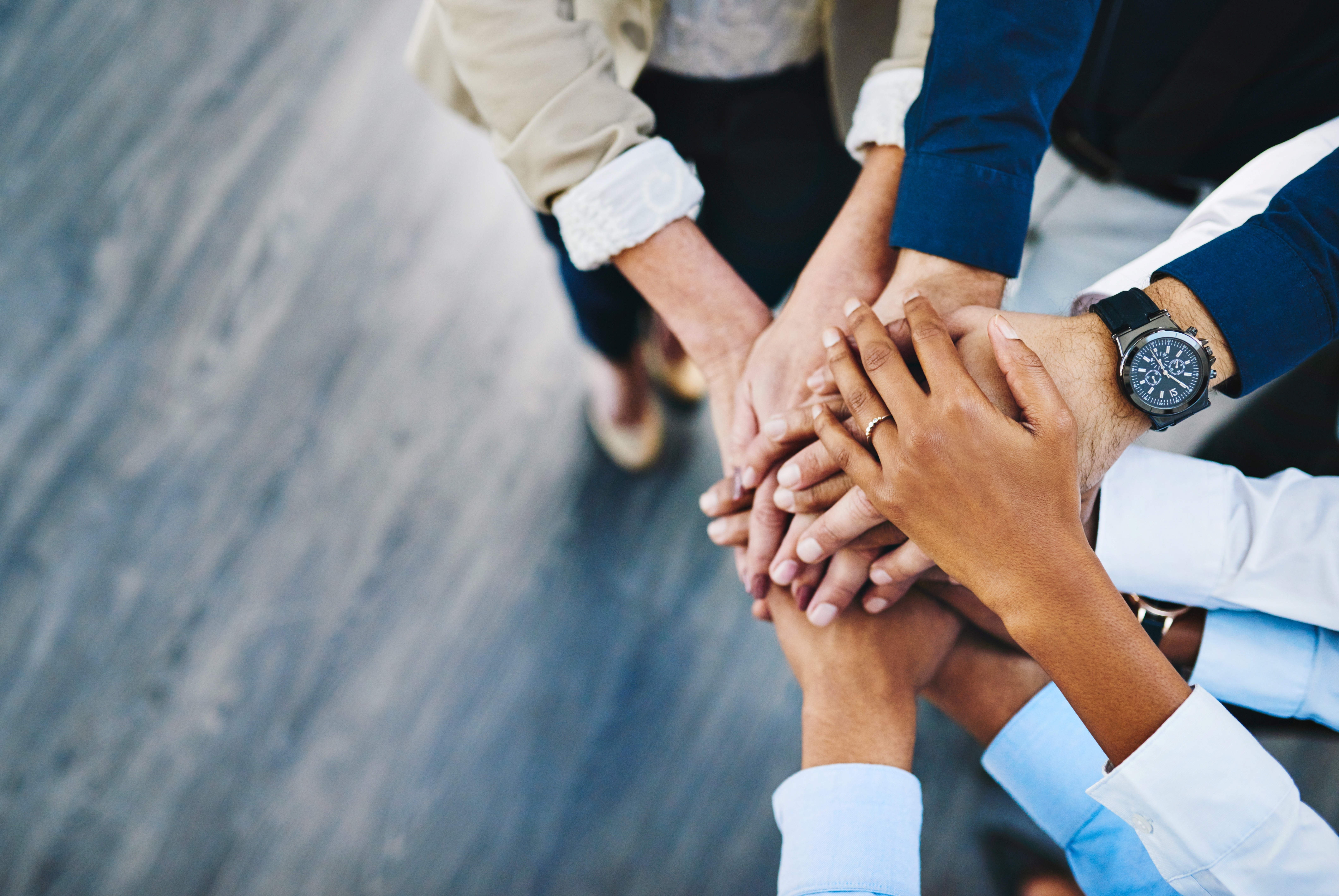 Several people stacking their hands together in a gesture of teamwork and unity.