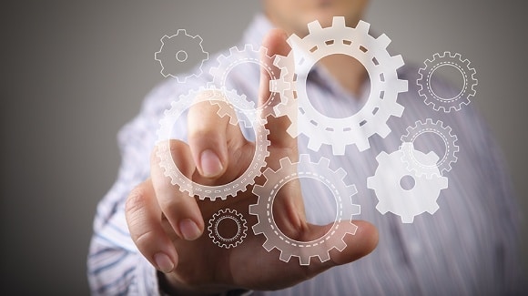 A person touches floating digital gears, symbolizing interconnected business processes.