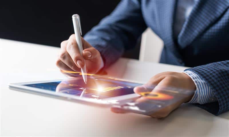 Person using a stylus on a tablet displaying graphs and digital data.