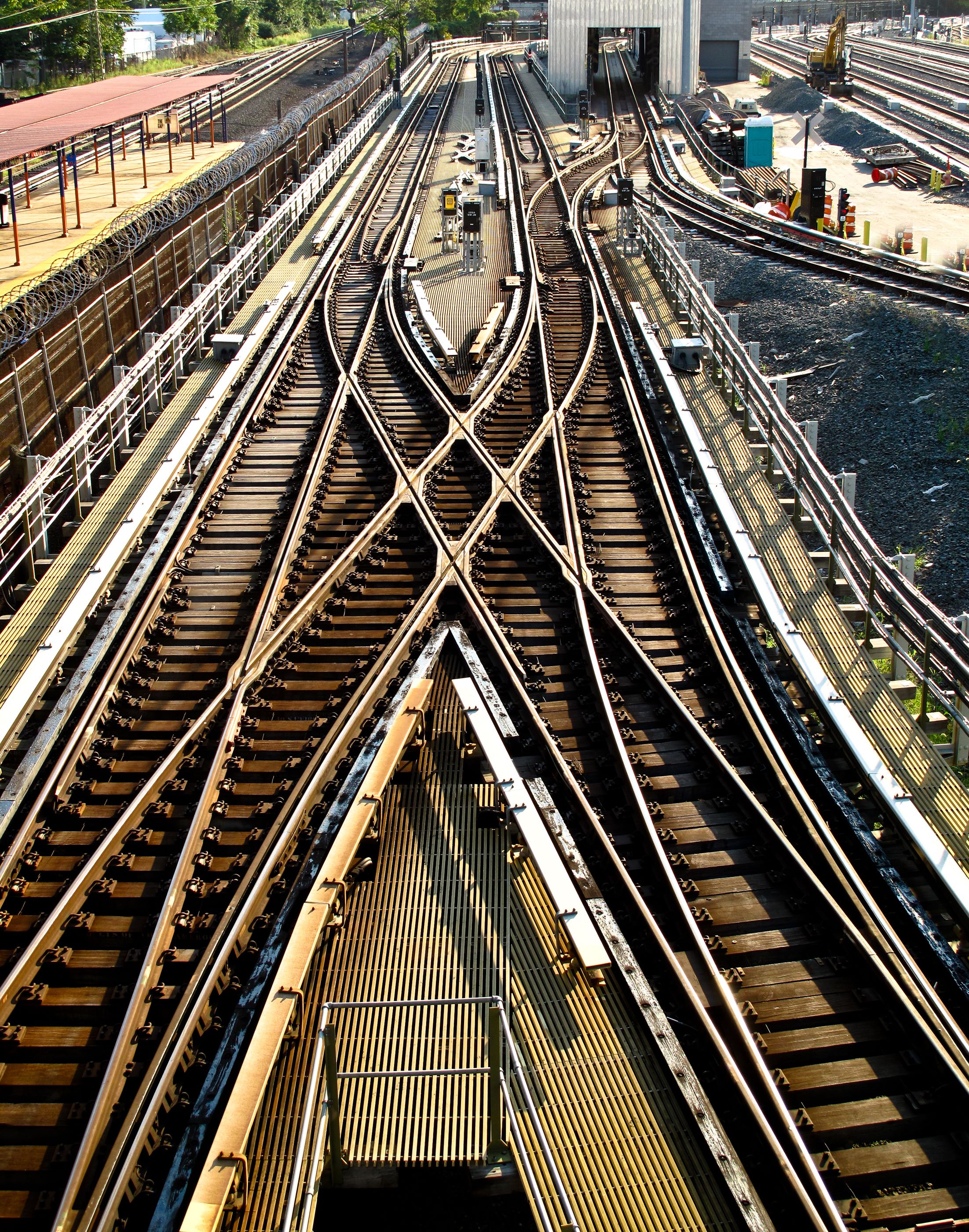 Multiple railroad tracks intersect and diverge at a busy rail yard, viewed from above.