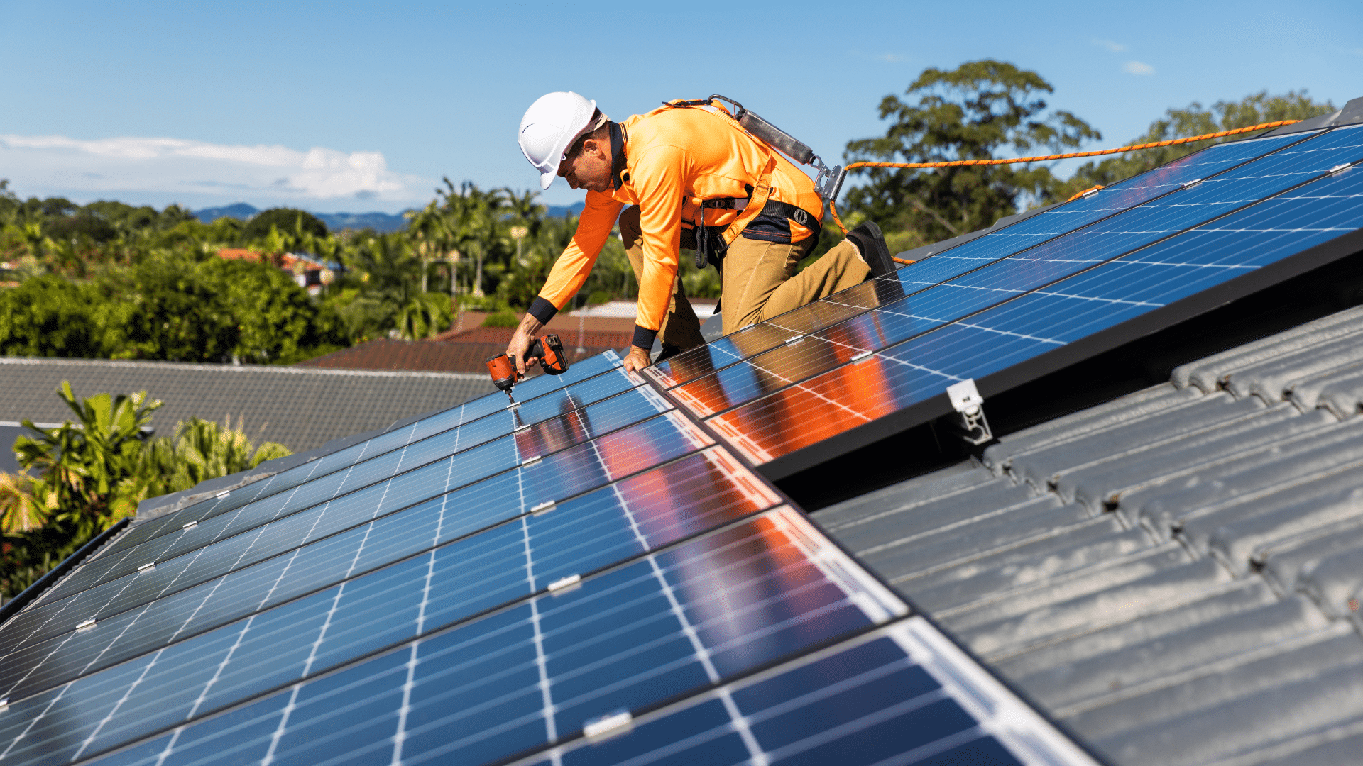 Website blog covers – Energy (26) Worker installing solar panels on a roof under a clear blue sky.