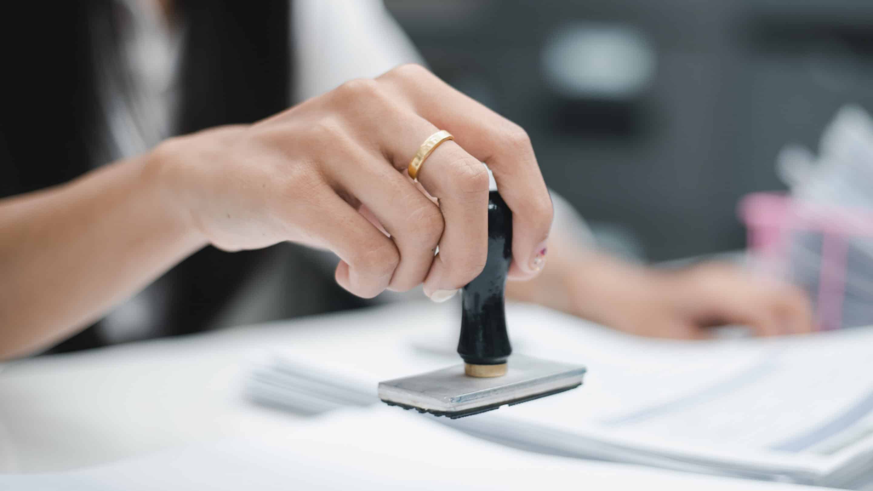 A person stamping documents at a desk in an office environment.